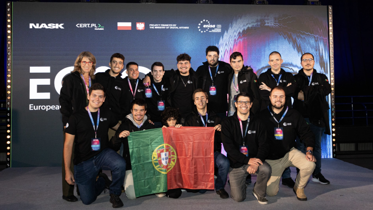 15 people posing for a team portrait, holding a Portuguese flag